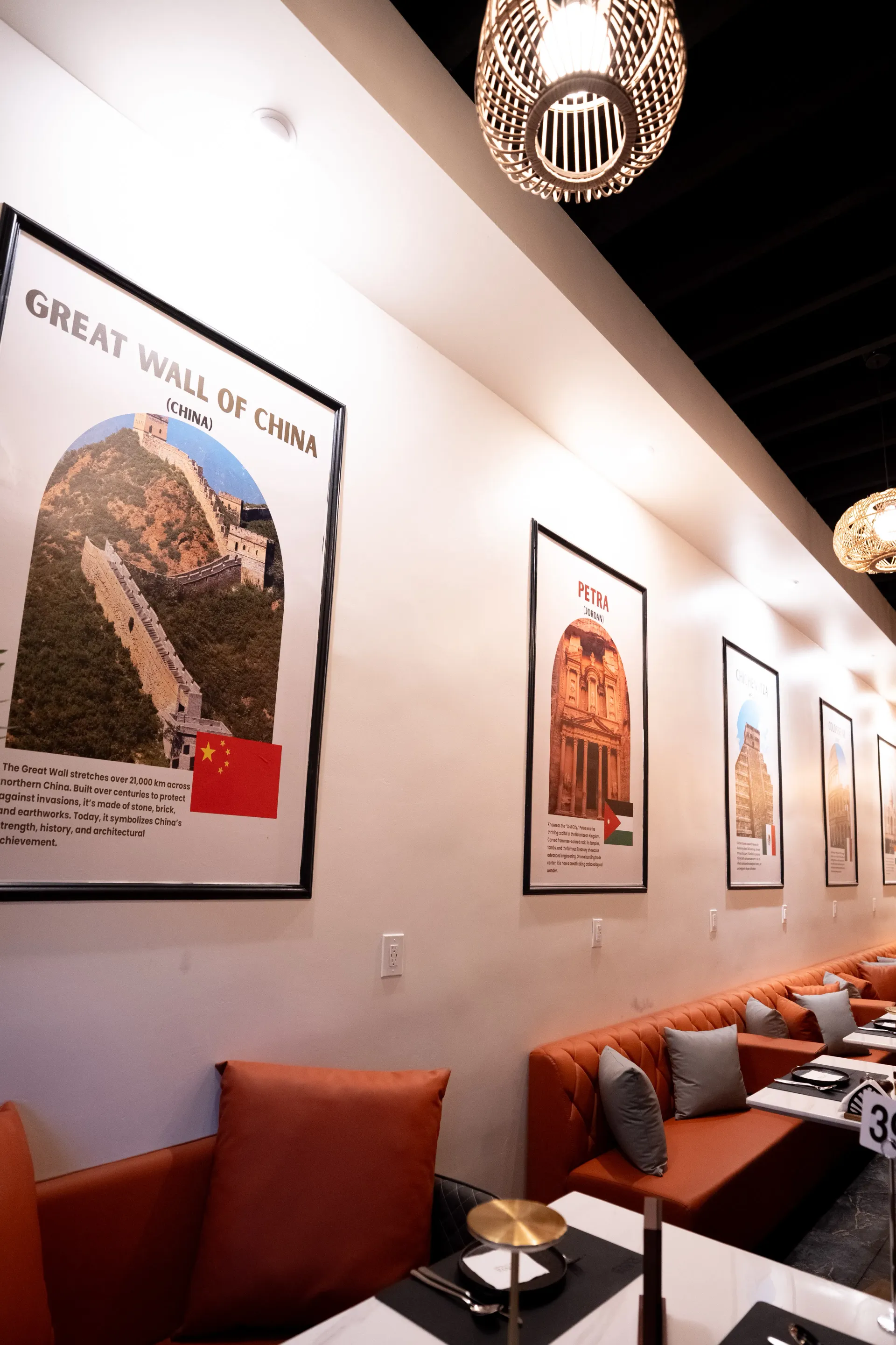 DUNYA terracotta leather booths beneath Seven Wonders travel posters